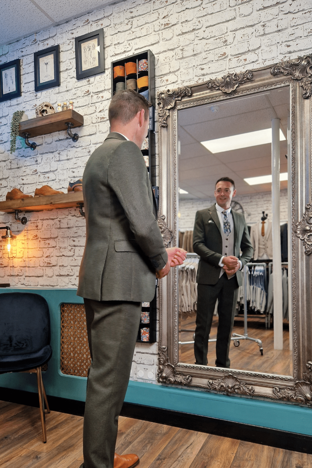 Groom standing in front of the mirror in his wedding suit
