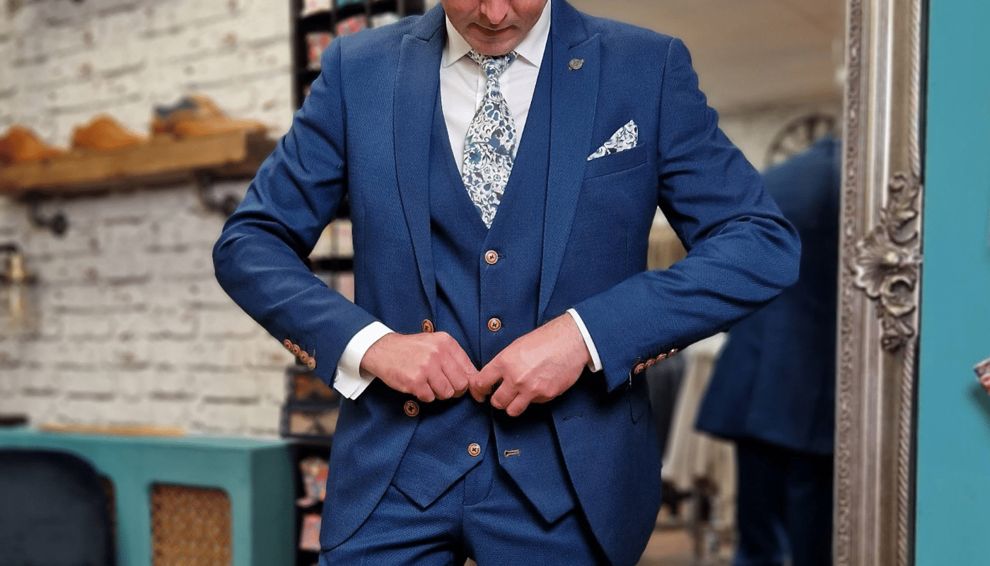 A groom fastening his waistcoat buttons on his wedding suit